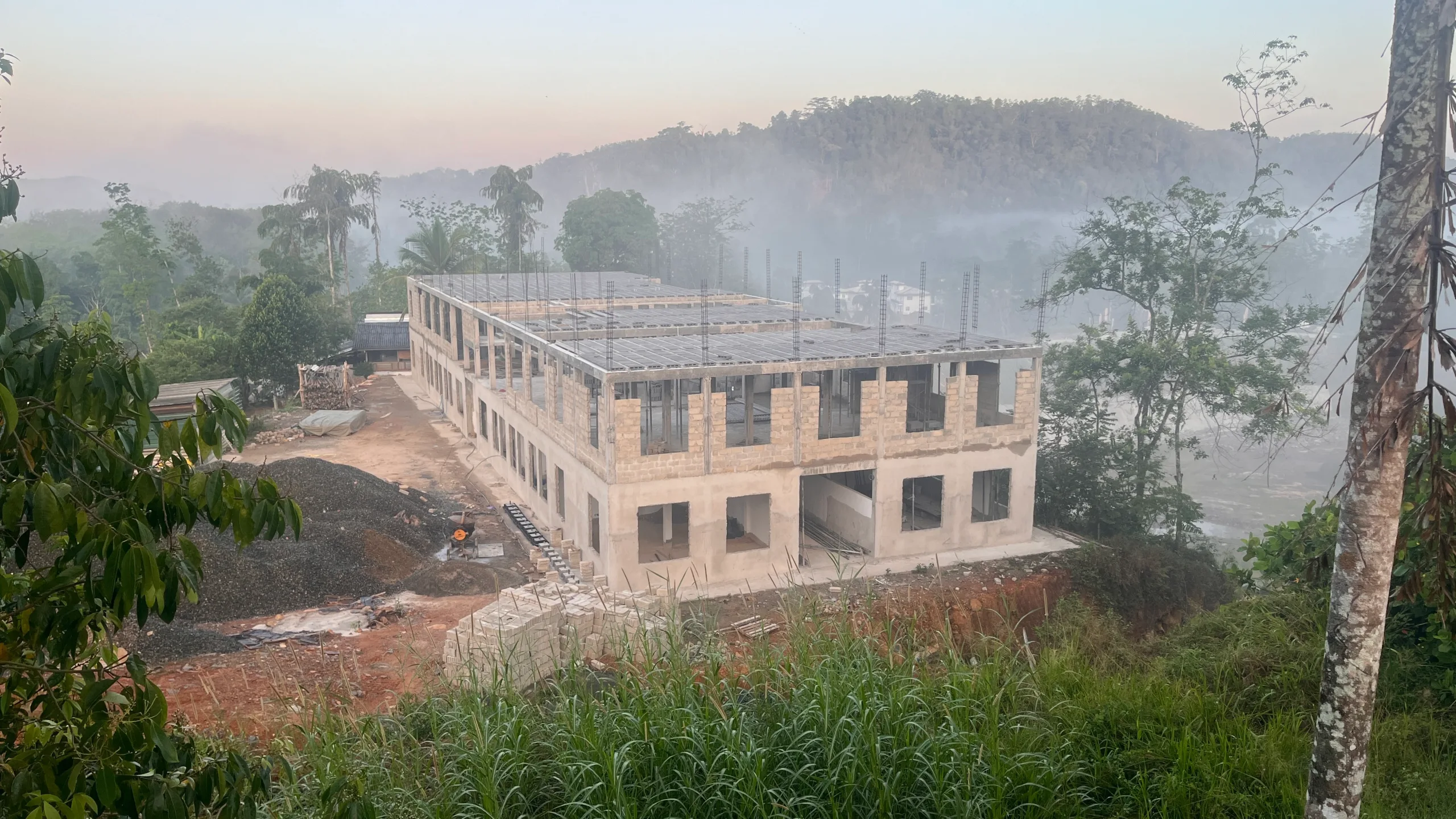 Elevated aerial view of the entire two-story school building of Noble International School, under construction surrounded by natural greenery