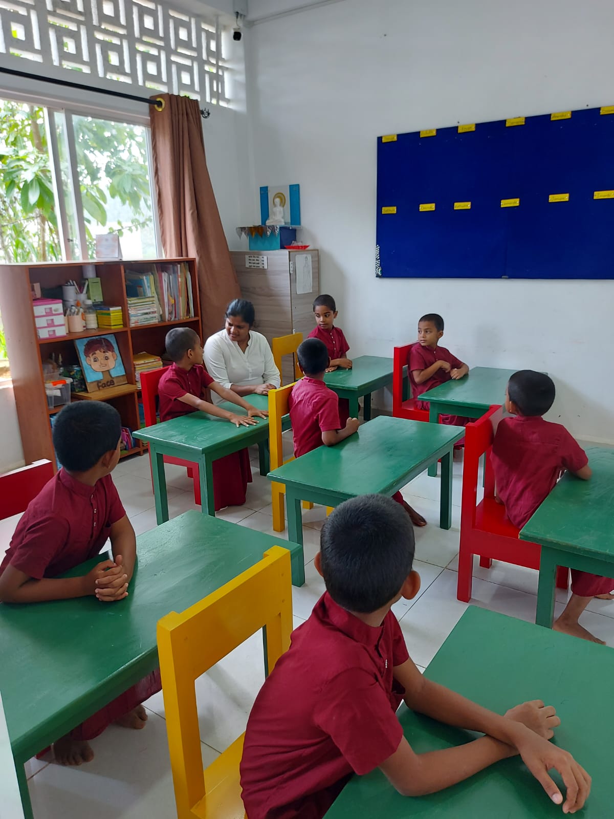 Primary school students sitting at study desks and chairs donated to Noble International School