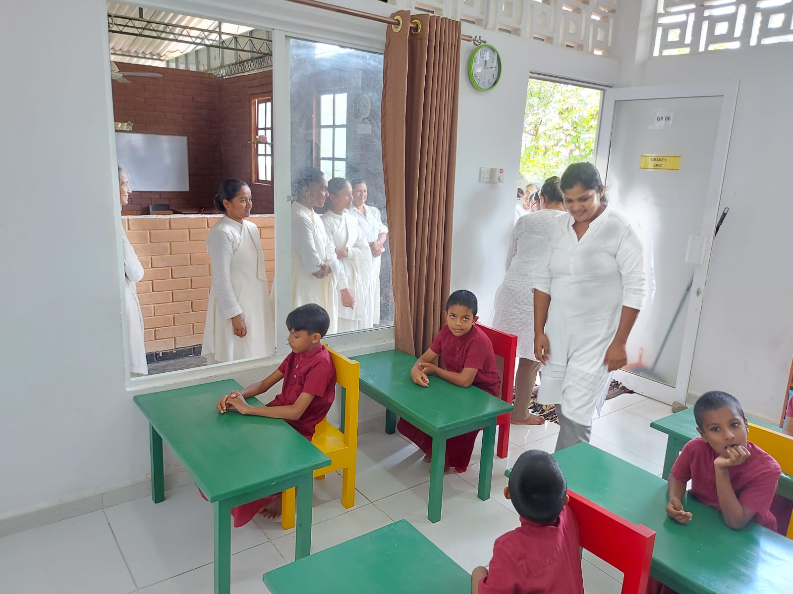 Students sitting at newly donated green desks and colorful chairs inside a Noble International School classroom