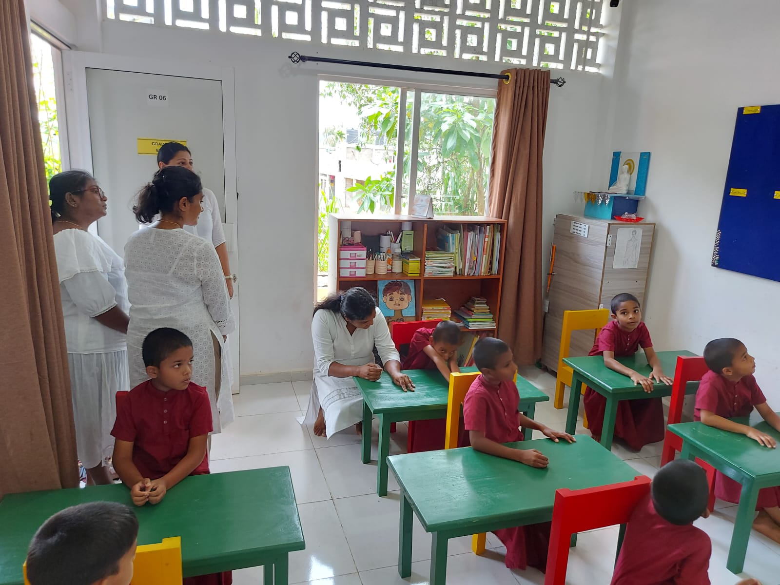 Teachers and students in a primary classroom equipped with newly donated desks and chairs